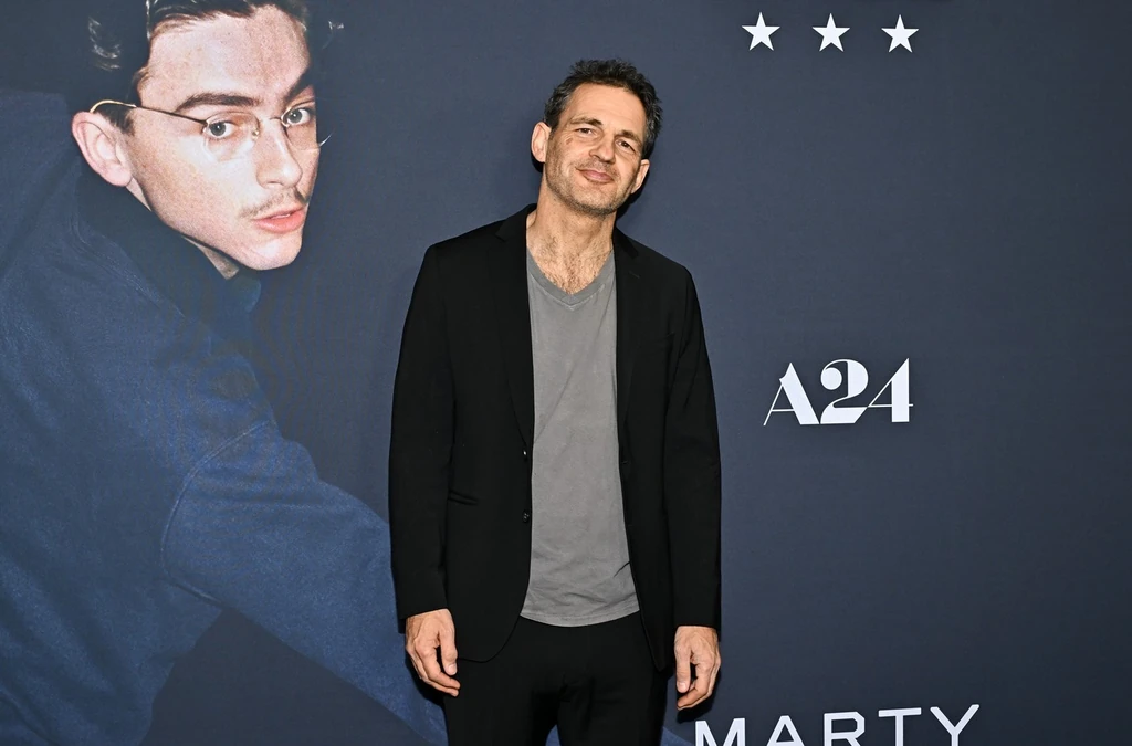 Röhrig Géza a Marty Supreme bemutatóján, a plakáton mögötte Timothée Chalamet (Fotó: Profimedia)